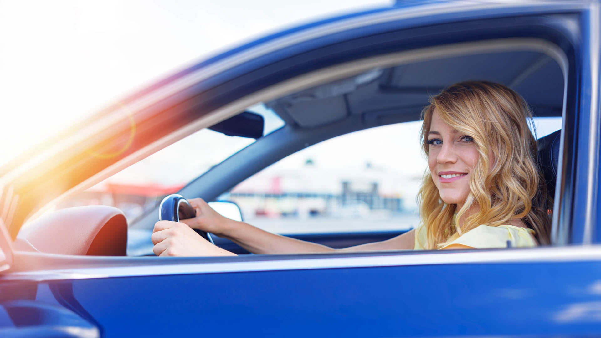FAQ / Hilfe 1 Fahrerin im blauen Auto blickt lächelnd aus dem Fenster